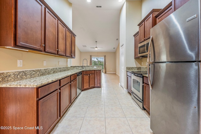 kitchen featuring light stone countertops, sink, ceiling fan, kitchen peninsula, and appliances with stainless steel finishes