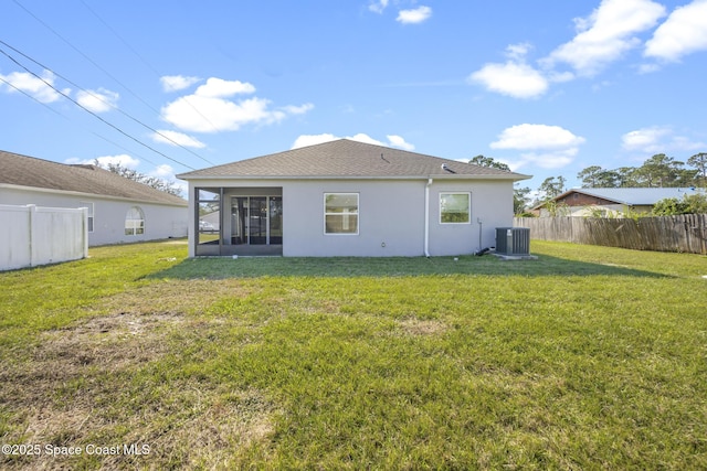 rear view of property featuring central AC unit, a lawn, and a sunroom