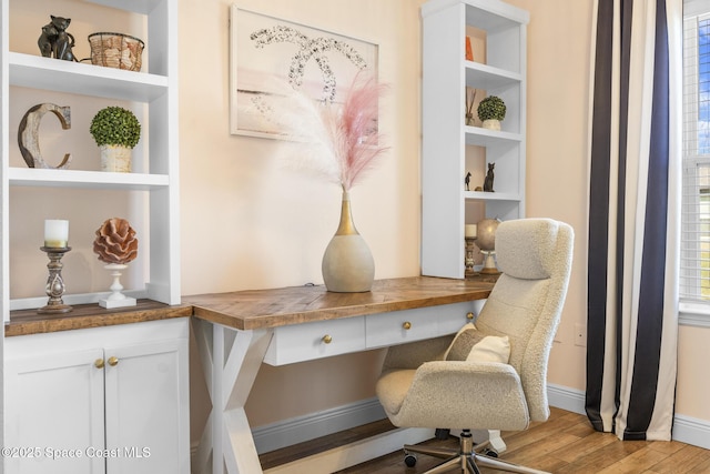 office with built in shelves, light hardwood / wood-style flooring, and built in desk