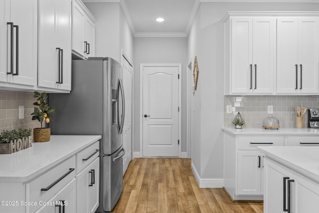 kitchen featuring decorative backsplash, light wood-type flooring, ornamental molding, white cabinets, and stainless steel fridge with ice dispenser