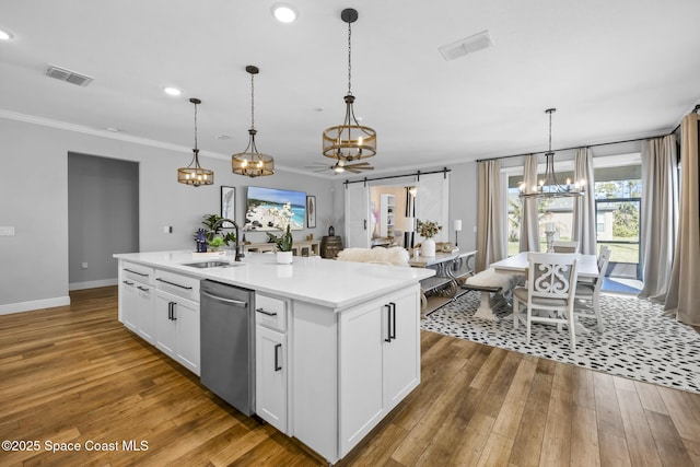 kitchen featuring white cabinets, a kitchen island with sink, sink, a barn door, and dishwasher