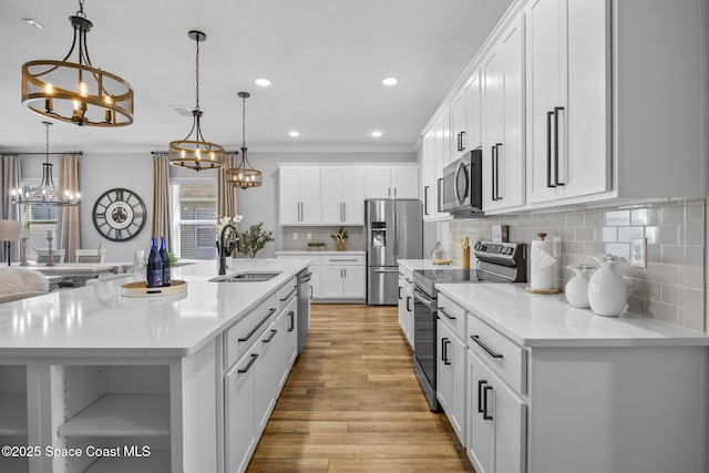 kitchen with sink, decorative light fixtures, a kitchen island with sink, white cabinets, and appliances with stainless steel finishes