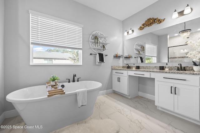 bathroom featuring a washtub, vanity, a wealth of natural light, and a notable chandelier