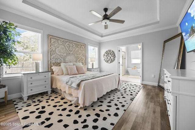 bedroom with ensuite bath, a raised ceiling, ceiling fan, and hardwood / wood-style flooring