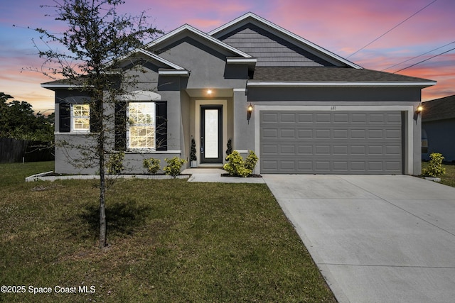 view of front facade with a yard, an attached garage, driveway, and stucco siding