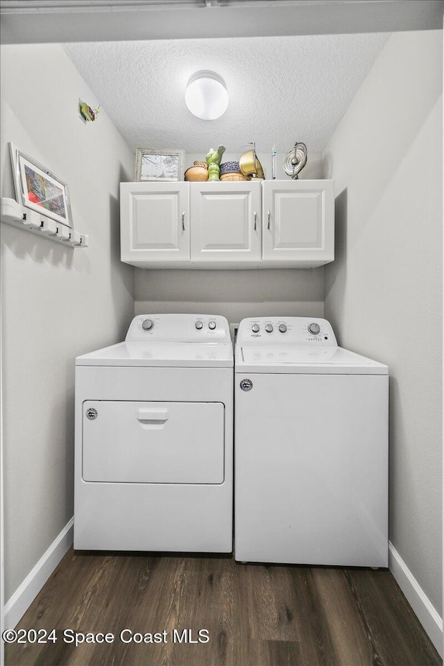 laundry room featuring washer and clothes dryer, cabinets, a textured ceiling, and dark wood-type flooring