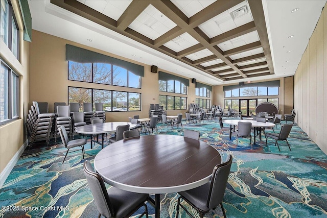 dining room with beamed ceiling, a towering ceiling, plenty of natural light, and coffered ceiling