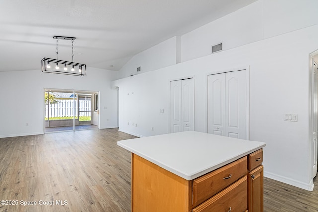 kitchen with light hardwood / wood-style floors, pendant lighting, a center island, and lofted ceiling