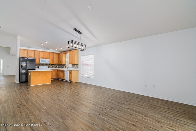 kitchen featuring vaulted ceiling, dark wood-type flooring, decorative light fixtures, and white appliances