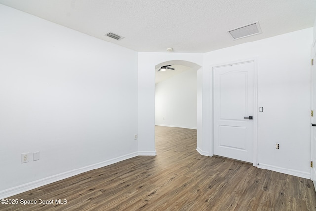 unfurnished room with a textured ceiling, ceiling fan, and dark hardwood / wood-style flooring