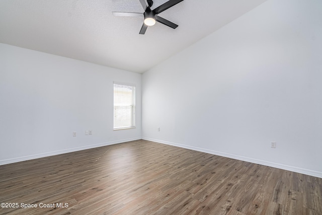 empty room featuring ceiling fan, dark wood-type flooring, and vaulted ceiling