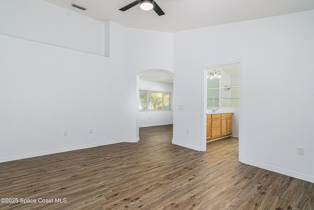 empty room with ceiling fan with notable chandelier and hardwood / wood-style flooring