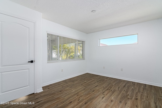 unfurnished room with dark wood-type flooring and a textured ceiling