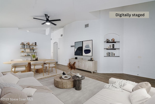 living room featuring ceiling fan, wood-type flooring, built in features, and vaulted ceiling