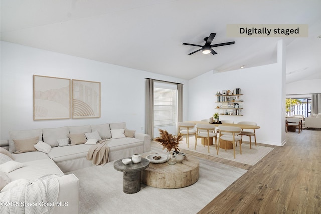 living room with ceiling fan, vaulted ceiling, and hardwood / wood-style flooring