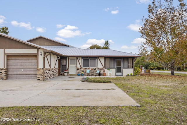 view of front of home with a sunroom, a garage, and a front lawn