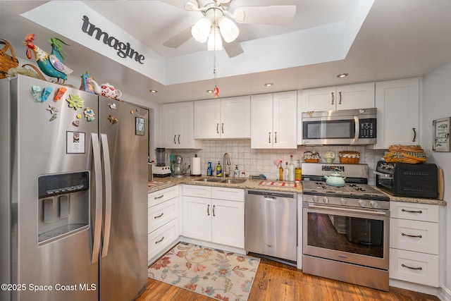 kitchen with decorative backsplash, light wood-type flooring, stainless steel appliances, sink, and white cabinetry