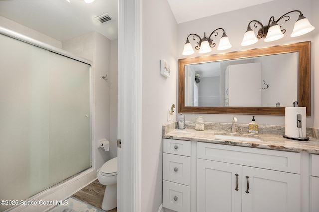 bathroom with hardwood / wood-style floors, vanity, toilet, and an enclosed shower