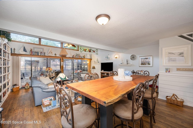 dining area featuring wood-type flooring and a textured ceiling