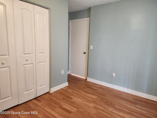 unfurnished bedroom featuring a closet, a textured ceiling, and light wood-type flooring