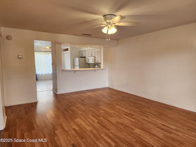 unfurnished living room featuring a textured ceiling, hardwood / wood-style flooring, and ceiling fan