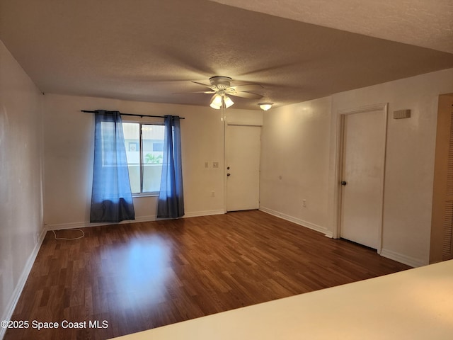 unfurnished room with ceiling fan, dark hardwood / wood-style flooring, and a textured ceiling