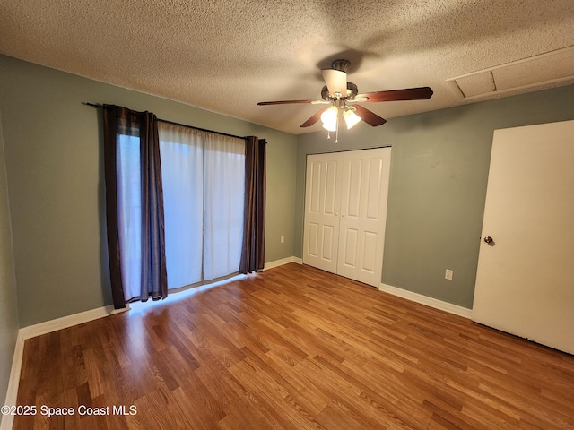 unfurnished bedroom featuring ceiling fan, light wood-type flooring, a textured ceiling, and a closet