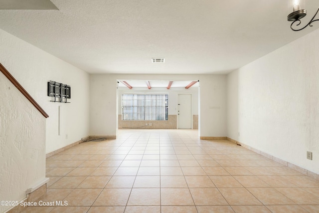 unfurnished room featuring light tile patterned flooring and a textured ceiling