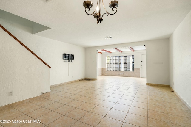 unfurnished living room with a notable chandelier and light tile patterned flooring