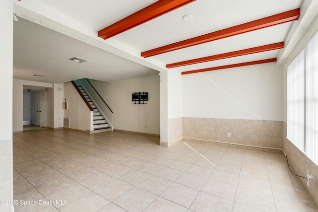 tiled empty room featuring beamed ceiling