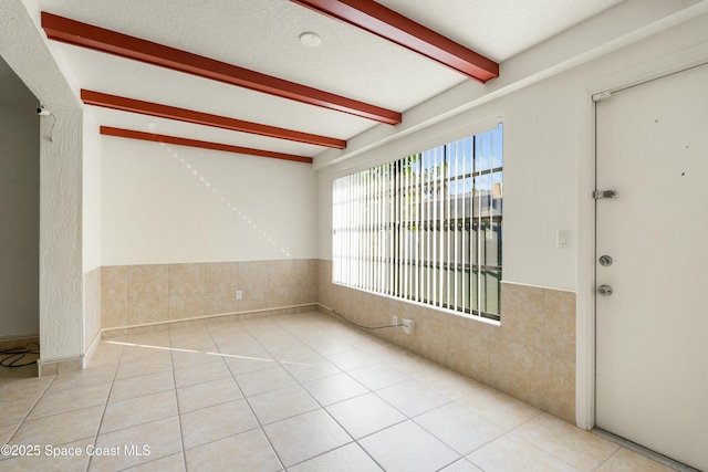 interior space featuring tile walls, beamed ceiling, and light tile patterned floors