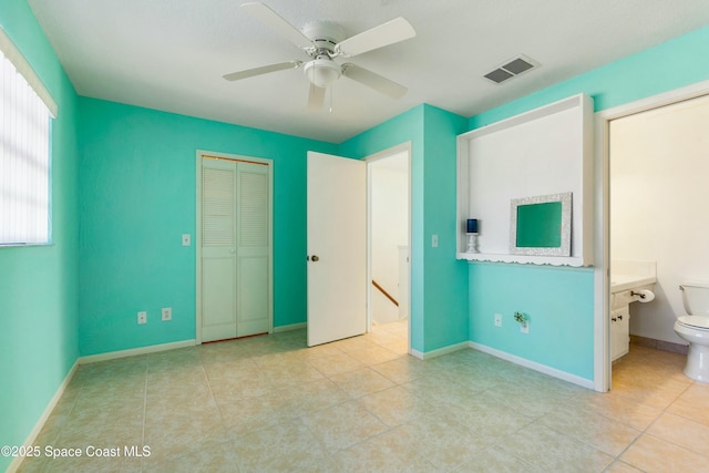 unfurnished bedroom featuring light tile patterned floors, ensuite bath, and ceiling fan