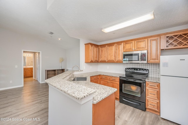 kitchen featuring light stone counters, kitchen peninsula, black electric range, and white fridge