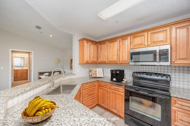 kitchen featuring black electric range oven, vaulted ceiling, light stone countertops, and sink