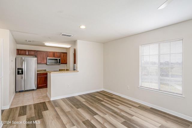 kitchen featuring kitchen peninsula, appliances with stainless steel finishes, light hardwood / wood-style floors, and plenty of natural light