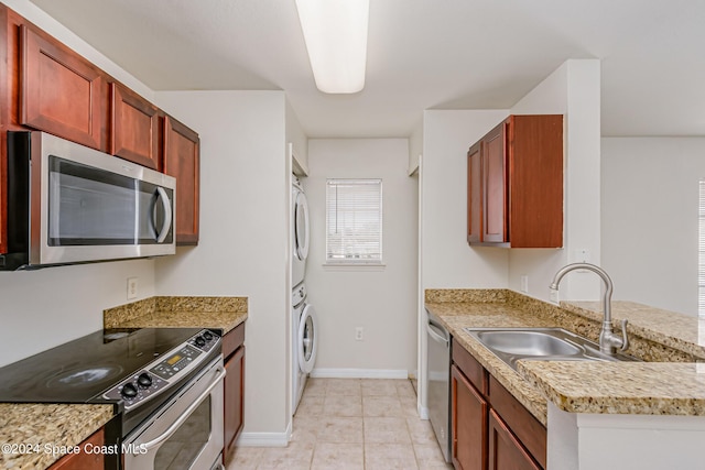 kitchen with sink, stainless steel appliances, kitchen peninsula, stacked washer / drying machine, and light tile patterned floors