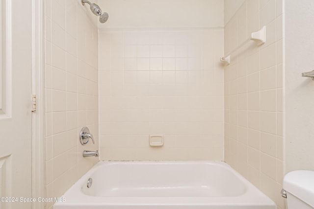 bathroom with tiled shower / bath combo and toilet