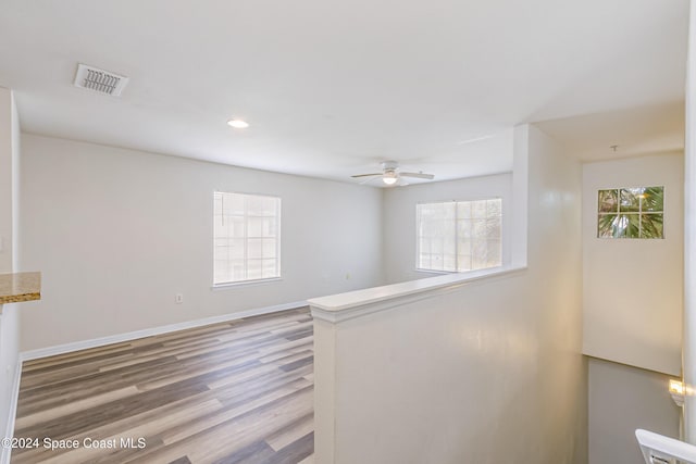 empty room with ceiling fan, a healthy amount of sunlight, and wood-type flooring