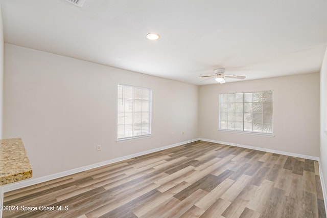 empty room with ceiling fan and light hardwood / wood-style flooring