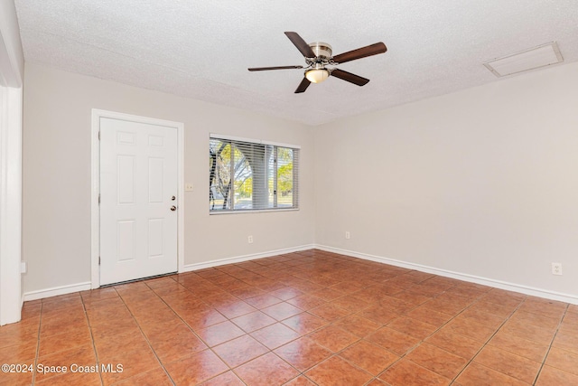 tiled empty room featuring ceiling fan and a textured ceiling