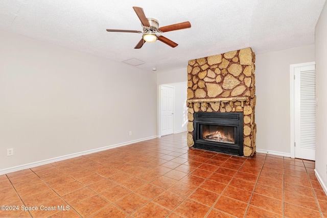 unfurnished living room with tile patterned floors, ceiling fan, a fireplace, and a textured ceiling