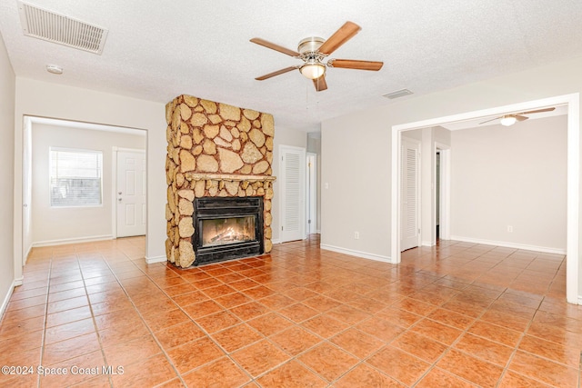 unfurnished living room featuring tile patterned floors, ceiling fan, a fireplace, and a textured ceiling