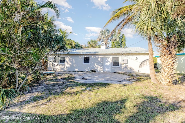 back of house with a patio and a lawn