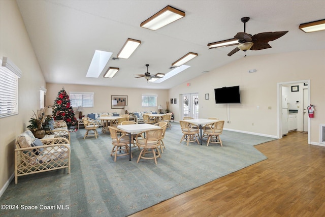 dining space featuring dark hardwood / wood-style flooring, lofted ceiling with skylight, ceiling fan, and plenty of natural light