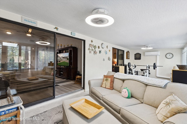 living room featuring a textured ceiling, a wall unit AC, and ceiling fan