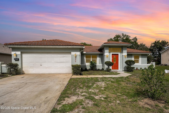 view of front of home featuring a tile roof, driveway, an attached garage, and stucco siding