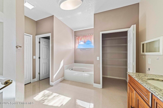 bathroom with vanity, a textured ceiling, and tiled bath