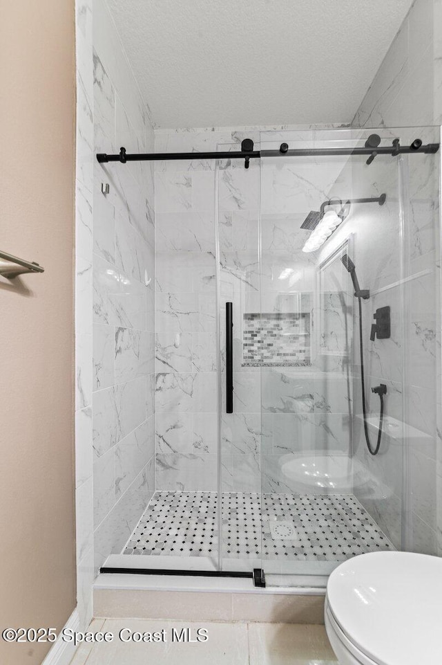 bathroom featuring tile patterned floors, toilet, an enclosed shower, and a textured ceiling