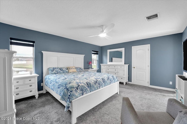 bedroom with ceiling fan, a textured ceiling, and dark colored carpet