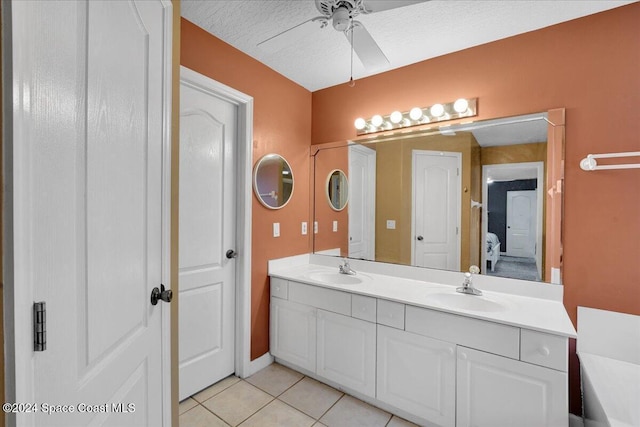 bathroom with tile patterned floors, ceiling fan, vanity, and a textured ceiling